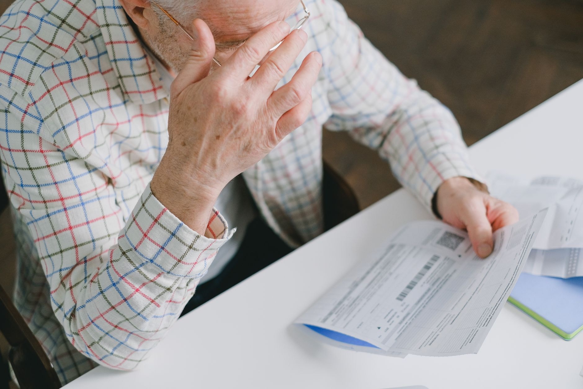 Un pensionar analizează cu îngrijorare documentele primite privind recalcularea pensiei